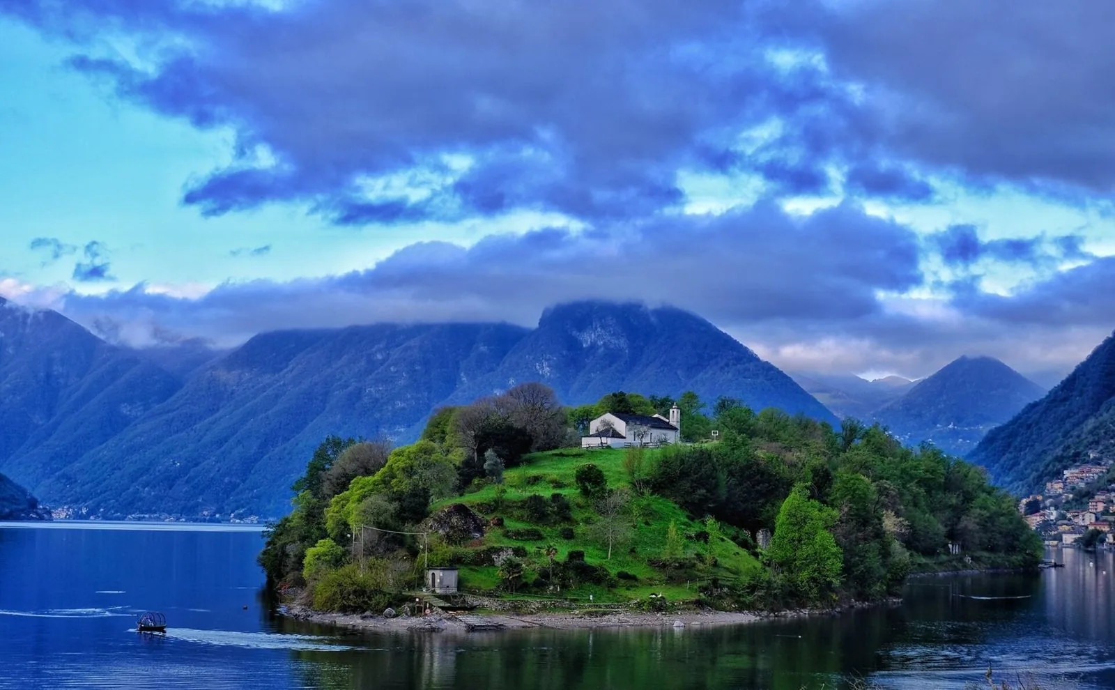 La chiesa di San Giovanni Battista sull'Isola Comacina tra il verde, con il lago e le montagne