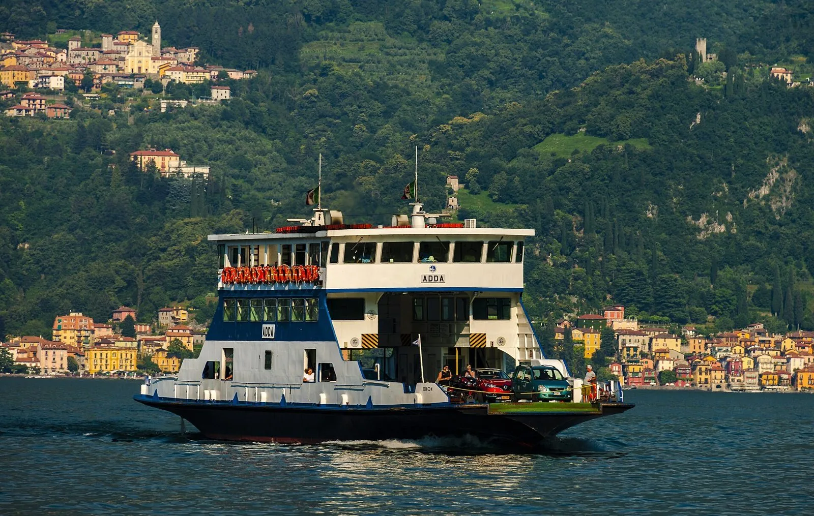 Il traghetto Adda con le auto a bordo attraversa il Lago di Como davanti a Varenna
